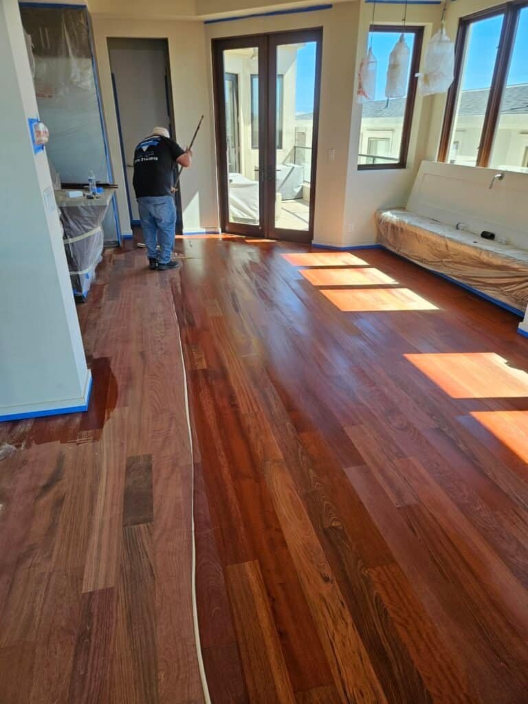 Polished mahogany hardwood flooring in a modern living room under construction.