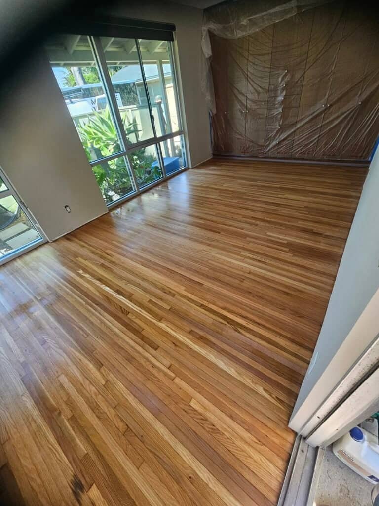 Hardwood floors installation in a bright living room with sliding glass doors, showcasing beautiful GTO Hardwood Floors.